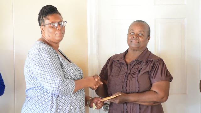 Single Parent Support Group member Verline Amory presents a cheque to Agnes Nisbett on behalf of her grandson Madikai Nisbett to assist with medical expenses on March 23, 2017 at the Department of Social Services at Park Range in Charlestown